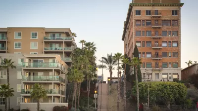 Vintage multi-story brick apartment building and modern concrete and glass apartment building separated by a steep public stairway in Los Angeles, California.
