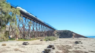 Amtrak train passing over tall trestle bridge on California coast at Gaviota Beach.