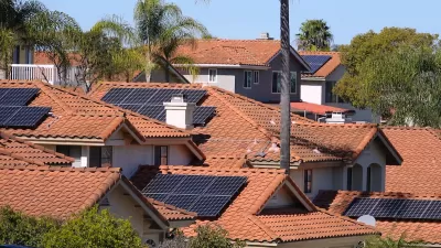 Photovoltaic solar panels on red-tile rooftops in California neighborhood.