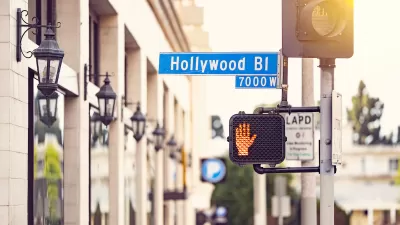 Close-up shot of Hollywood Blvd street sign and pedestrian crossing signal with red 'Don't walk' hand lit.