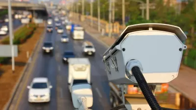Automated traffic enforcement camera mounted above roadway with blurred image of roadway and cars below