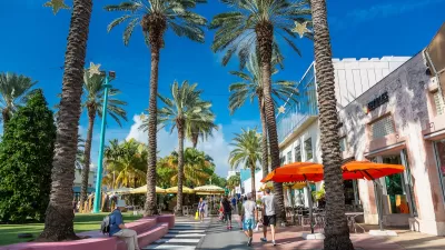 Pedestrian street with colorful patio umbrellas and tall palm trees in Miami, Florida.