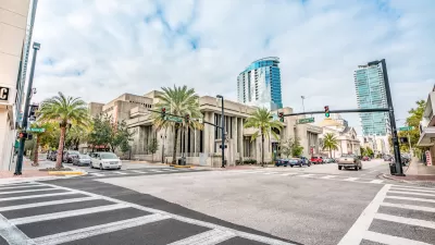 View of empty zebra crosswalk at intersection in Orlando, Florida with glass towers in background.