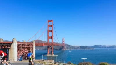 Two cyclists on a paved bike path overlooking the Golden Gate Bridge, San Francisco, California.