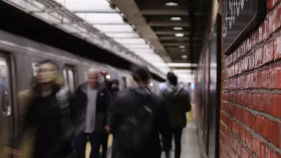 Busy New York City subway platform with blurred people walking in and out of trains and close-up on red brick wall on right.