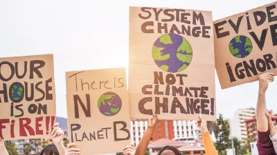 Close-up of signs calling for action on climate change being help up by multiple people outdoors.