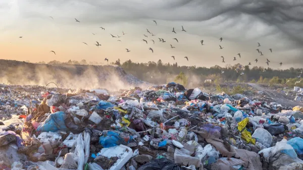 Large pile of unsorted garbage in landfill with birds flying above at sunrise or sunset.
