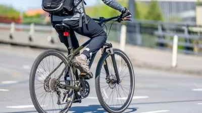 Close-up of person on bike wearing backpack riding on city street.