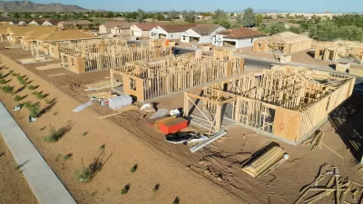 Aerial view of multiple wood-framed buildings under construction.