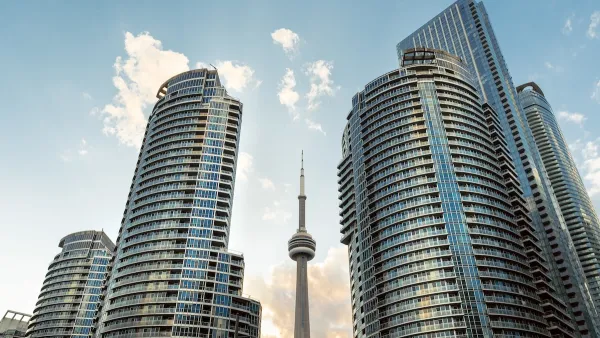 Tall modern condo buildings on both sides of CN Tower rising in middle.