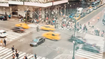 Aerial view of busy NYC crosswalk with pedestrians and blurred traffic.