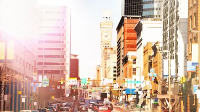 Wide, busy street with red bus lane in downtown Baltimore, Maryland.
