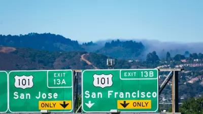 Close-up of green freeway signs pointing to US 101 to San Jose and San Francisco with foggy hills in background.