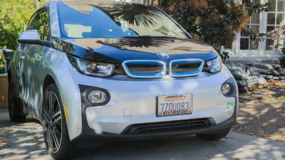 Silver electric BMW car parked in driveway of home in Oakland, California.