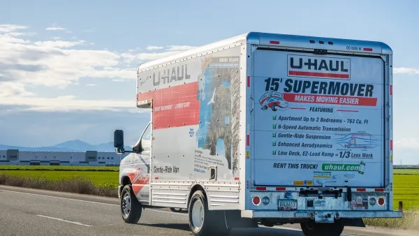 U-Haul truck on road with blurred grassy roadside in background.