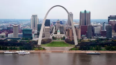 View of the Gateway Arch with Mississippi River in foreground and St. Louis skyline in background.