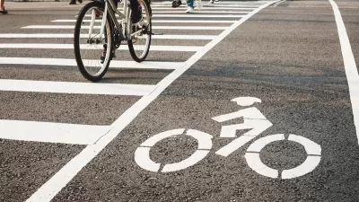 Low angle of pedestrians and a bicycle crossing the street at an urban crosswalk.