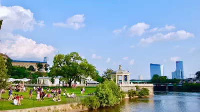 Riverfront park in Philadelphia with white gazebo and skyscrapers in background.