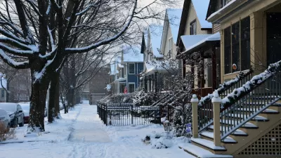 Snow covers a sidewalk and small homes on a Chicago street