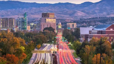 View of wide street in downtown Boise, Idaho with state capitol visible at end of street and blurred traffic going both directions at dusk.