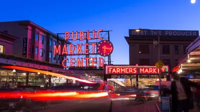 Pike Place Market in Seattle at twilight with neon market sign and cars passing through.