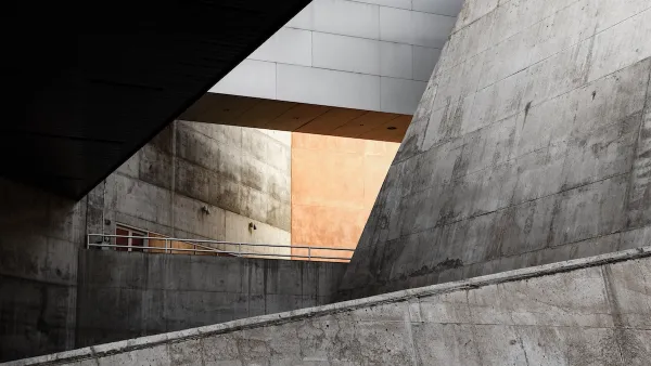 Concrete Brutalism building with slanted walls and light visible through an atrium.