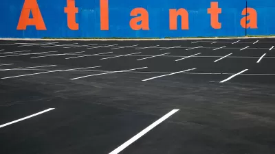 Empty asphalt parking lot with blue wall in background with Atlanta painted in orange letters.