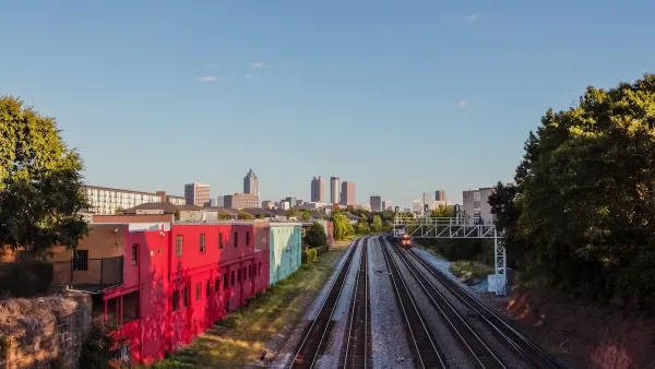 Train tracks with red building on left side and Atlanta high-rises visible in background.