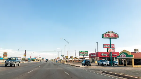 Wide multi-lane road in Alamogordo, New Mexico with Papa John's and other fast food restaurants along road.