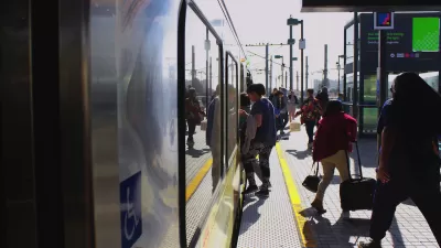 People boarding Los Angeles Metro train on outdoor platform.