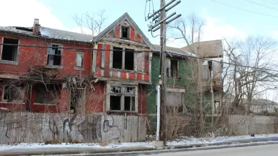 Vacant two-story red brick home in Detroit with missing windows.