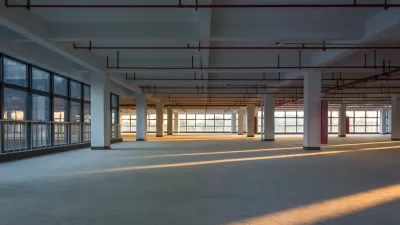 Large empty office building floor with columns and golden hour light.