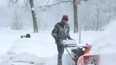 Man using snow plow during snowstorm.