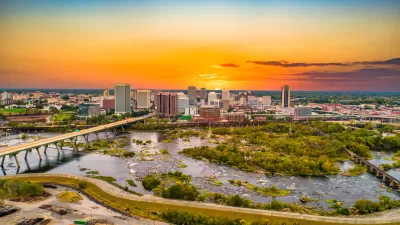 Aerial view of Richmond, Virginia skyline with river in foreground against sunset sky.