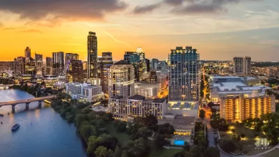 Austin, Texas skyline with river in foreground at sunset.