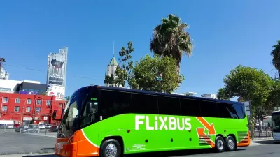 Green Flixbus bus parked on street in Los Angeles, California with palm trees and Hollywood buildings in background on sunny day.