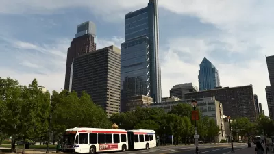 White city bus on road in Philadelphia, Pennsylvania with tall city buildings in background.