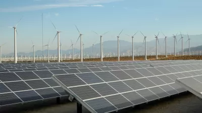 Large solar panel installation and wind turbines with Southern California desert mountains in background.