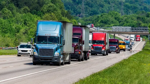 Line of multi-colored big rig trucks drivign down highway with other traffic including a yellow school bus.