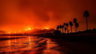 Palm trees on Santa Barbara beach against the red glow of a wildfire