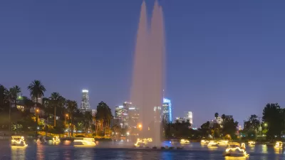 View of Echo Park Lake at night with artesian fountain and illuminated swan paddle boats and Los Angeles skyline in background
