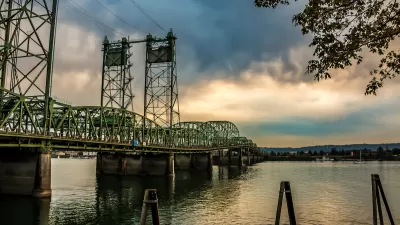 Green metal bridge over Columbia River between Oregon and Washington against cloudy sky.