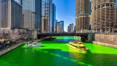 A boat floats on a bright green Chicago River lined by skyscrapers.