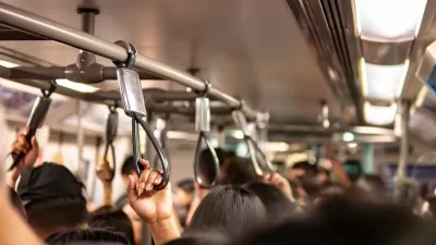 Close-up on passengers holding overhead straps on busy public transit bus.