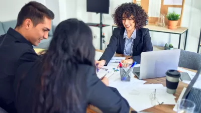 Couple on one side of desk with banker on other side looking at paperwork.