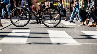 Low shot of pedestrians and a bike crossing a striped crosswalk.