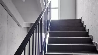 View of plain building staircase with light coming in from window on landing