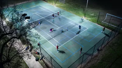 Aerial view of pickleball court with players illuminated for nighttime play
