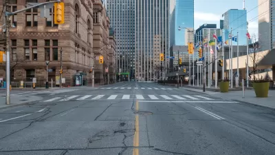 View straight down empty wide street in downtown Toronto, Canada with stoplights during Covid-19 pandemic.