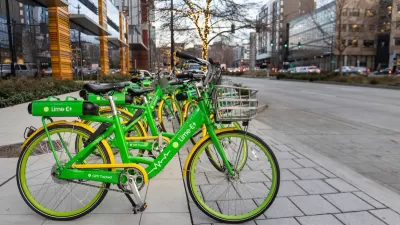Row of green Lime electric bikes parked on sidewalk in Seattle with tree decorated with string lights in background.
